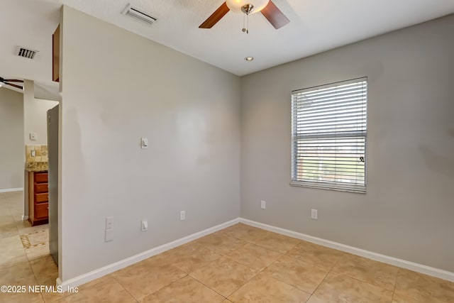 spare room featuring light tile patterned floors, visible vents, and a ceiling fan