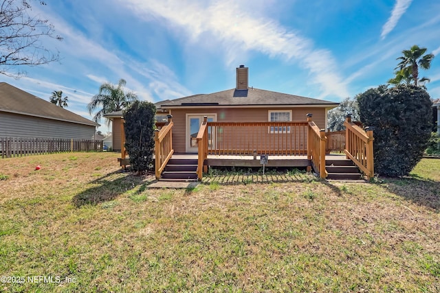 rear view of property with a yard, a chimney, a wooden deck, and fence