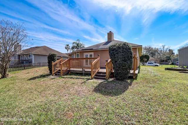 rear view of house featuring a yard, a chimney, fence, and a deck