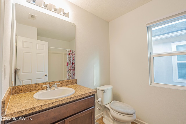 bathroom featuring visible vents, toilet, vanity, a shower with curtain, and baseboards