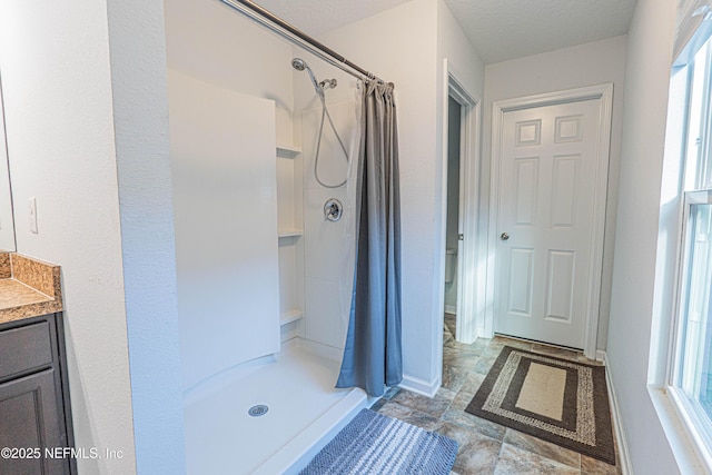 full bathroom with a stall shower, vanity, and baseboards