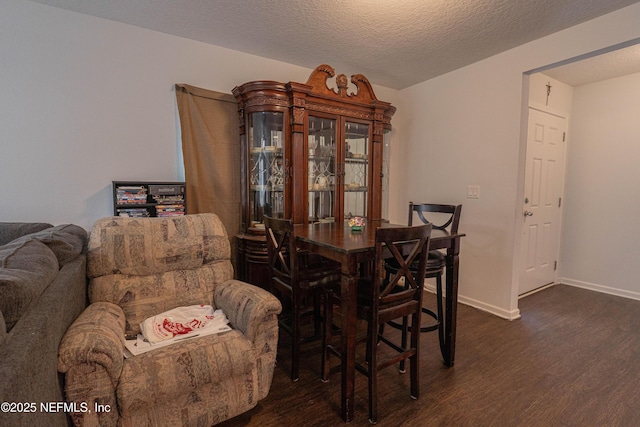 dining room featuring a textured ceiling, baseboards, and dark wood-type flooring