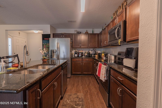 kitchen with visible vents, dark wood-type flooring, stainless steel appliances, a textured ceiling, and a sink