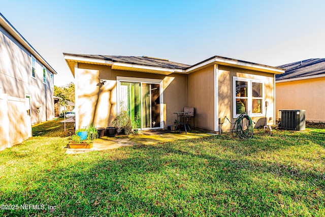 rear view of house with stucco siding, central AC, and a yard