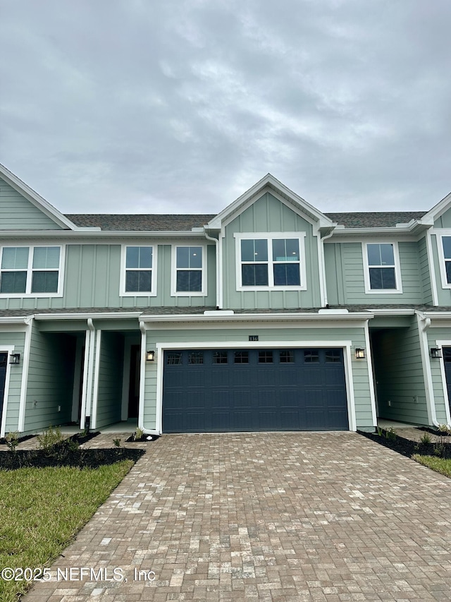 multi unit property featuring decorative driveway, board and batten siding, and an attached garage