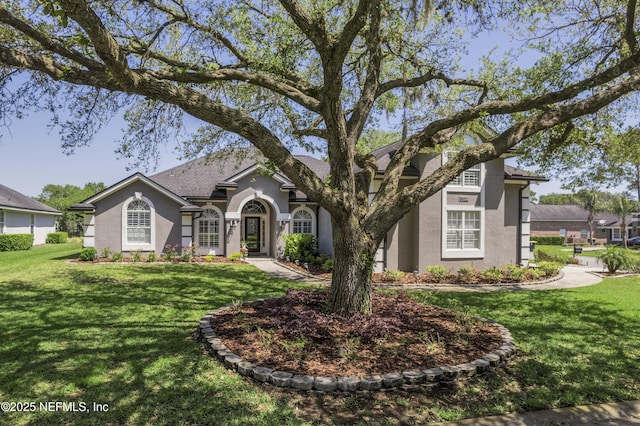 view of front of property featuring roof with shingles, a front yard, and stucco siding