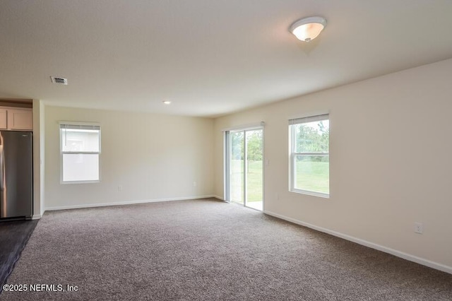 empty room with visible vents, baseboards, and dark colored carpet