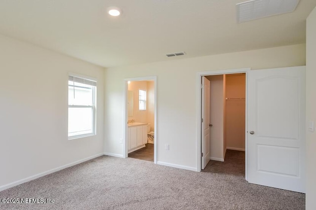 unfurnished bedroom featuring carpet, visible vents, a spacious closet, and baseboards