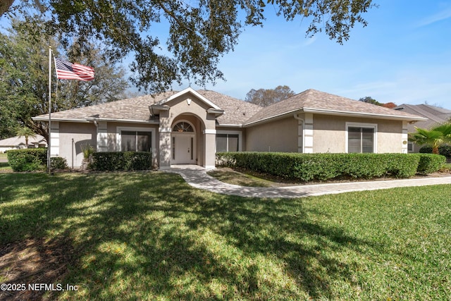 ranch-style home featuring stucco siding, a shingled roof, and a front yard