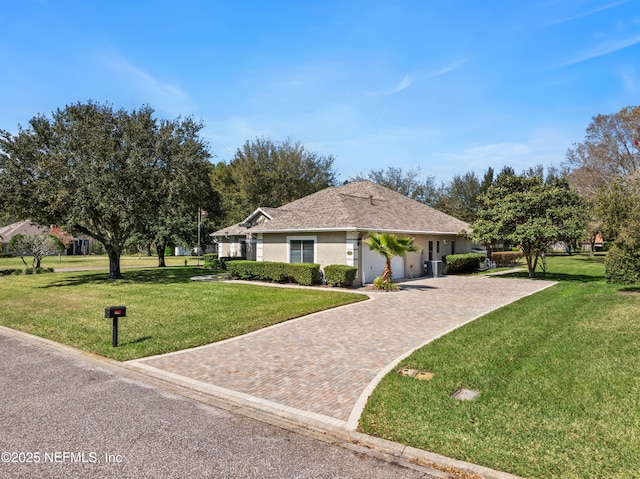 view of front of home with a front lawn, decorative driveway, an attached garage, and stucco siding