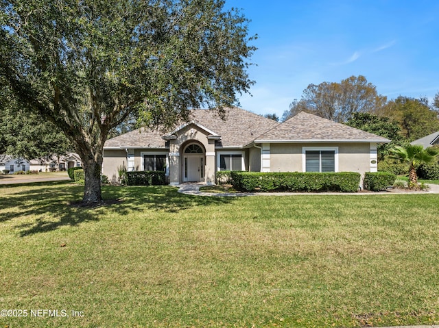 ranch-style house with roof with shingles, a front lawn, and stucco siding