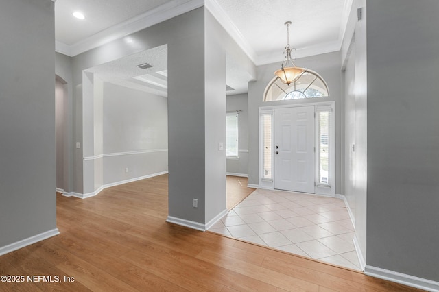 entryway with baseboards, light wood-style flooring, and crown molding