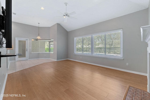 unfurnished living room featuring a fireplace with flush hearth, a ceiling fan, baseboards, vaulted ceiling, and light wood-style floors