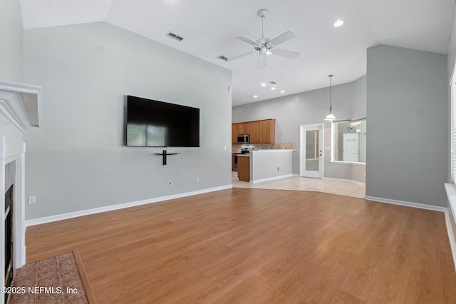 unfurnished living room with light wood finished floors, visible vents, a fireplace with flush hearth, ceiling fan, and baseboards