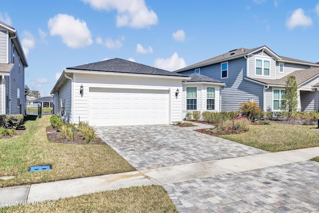 traditional-style home with a garage, a shingled roof, decorative driveway, and a front yard