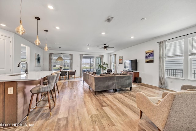 living area with light wood-style flooring, recessed lighting, a ceiling fan, baseboards, and visible vents