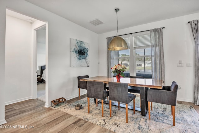 dining area featuring baseboards, visible vents, and wood finished floors