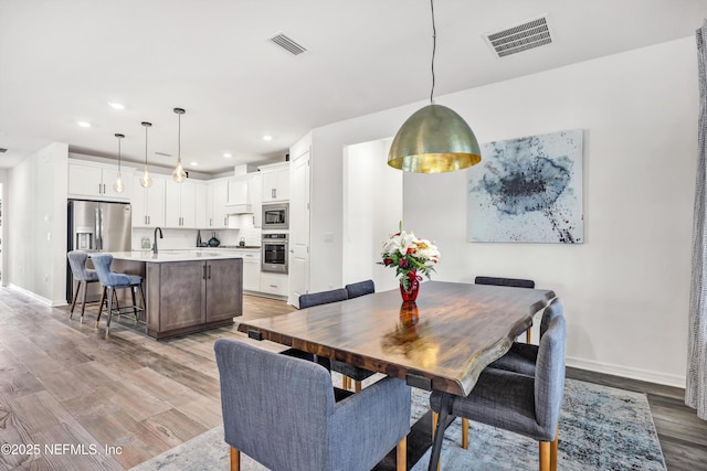 dining room featuring light wood-style floors, visible vents, and baseboards