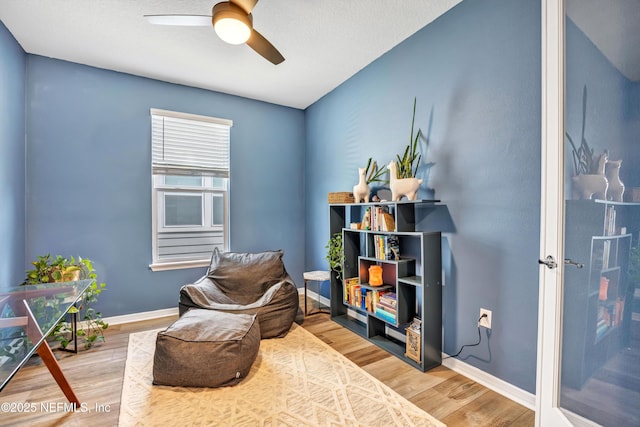 living area with ceiling fan, baseboards, and wood finished floors