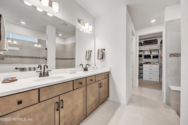 bathroom featuring a walk in closet, walk in shower, a sink, and tile patterned floors