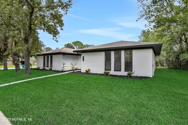 view of front of house with a shingled roof and a front lawn