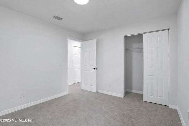 unfurnished bedroom featuring light colored carpet, a closet, visible vents, and baseboards