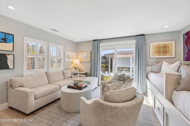 living room featuring visible vents, a textured ceiling, and wood finished floors