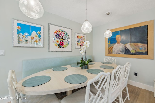 dining room featuring a textured ceiling, wood finished floors, and baseboards