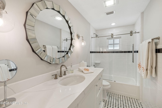 full bath featuring toilet, bath / shower combo with glass door, vanity, and visible vents