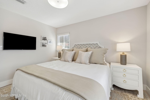 bedroom with light wood finished floors, visible vents, and baseboards