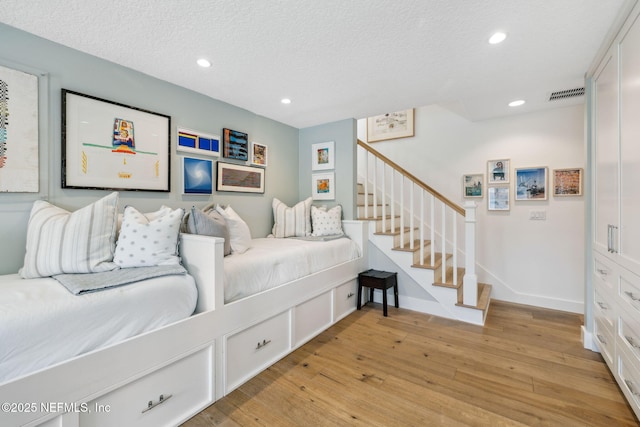 bedroom featuring a textured ceiling, recessed lighting, visible vents, baseboards, and light wood-type flooring