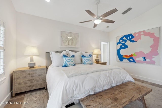 bedroom featuring lofted ceiling, visible vents, a ceiling fan, wood finished floors, and baseboards