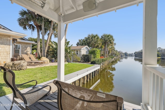 exterior space featuring a patio area, a water view, a lawn, and fence