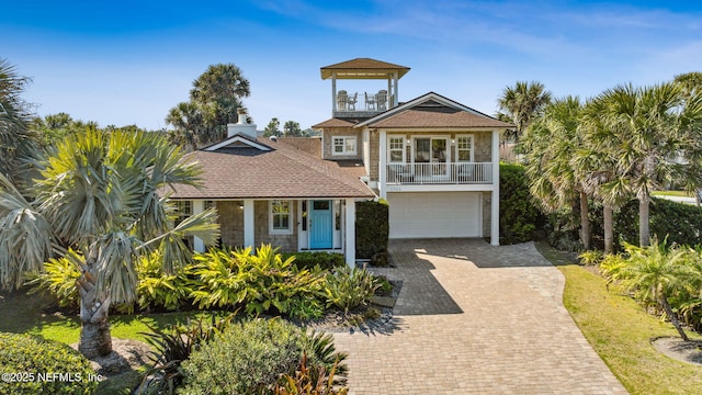 view of front facade with an attached garage, a balcony, and decorative driveway