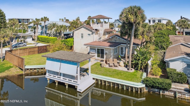 back of property featuring a water view, fence private yard, a residential view, and a lawn