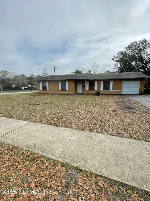 ranch-style home featuring driveway, an attached garage, and a front yard