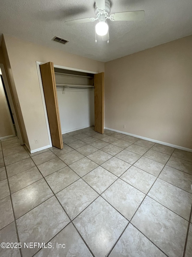 unfurnished bedroom with a closet, visible vents, light tile patterned flooring, a textured ceiling, and baseboards