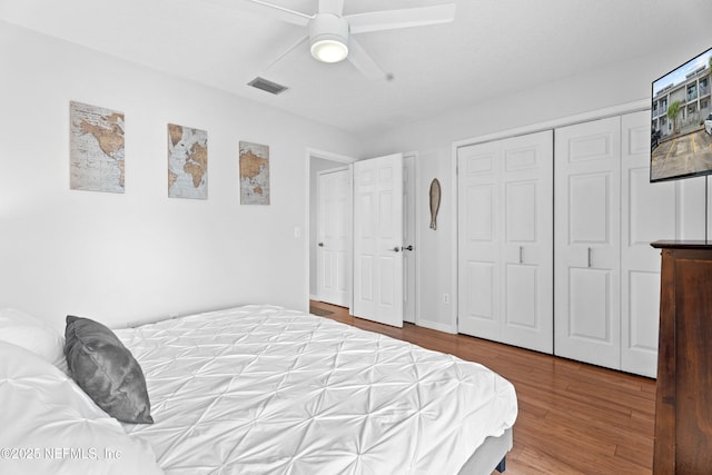 bedroom featuring a ceiling fan, visible vents, and wood finished floors