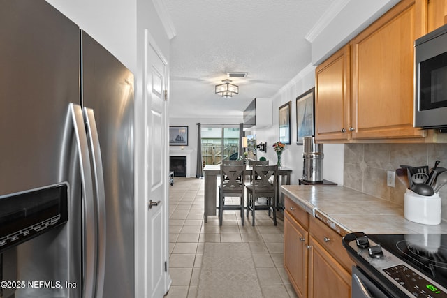 kitchen featuring stainless steel appliances, visible vents, backsplash, ornamental molding, and light tile patterned flooring