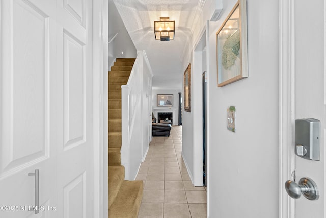 hallway with crown molding, stairway, a textured ceiling, and light tile patterned floors