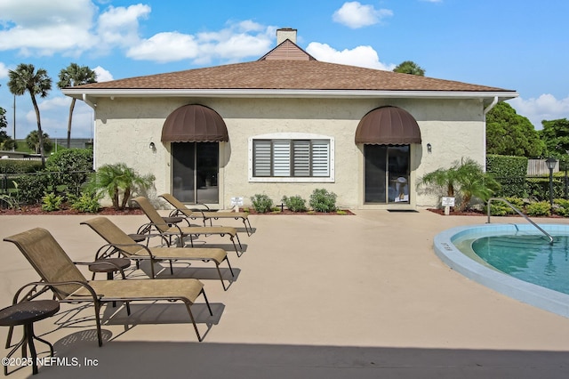 back of house featuring a patio area, a community pool, and stucco siding