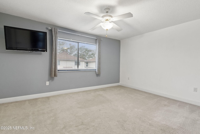 unfurnished room with a ceiling fan, light carpet, a textured ceiling, and baseboards