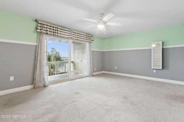 carpeted spare room featuring baseboards and a ceiling fan