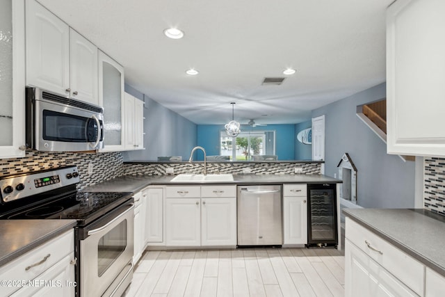 kitchen featuring beverage cooler, visible vents, dark countertops, appliances with stainless steel finishes, and a sink