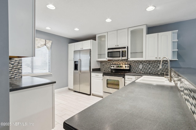 kitchen featuring open shelves, stainless steel appliances, dark countertops, white cabinets, and a sink