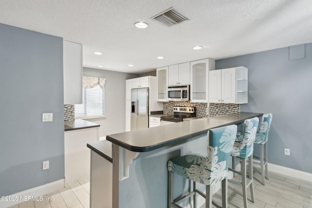 kitchen featuring a peninsula, visible vents, appliances with stainless steel finishes, open shelves, and dark countertops