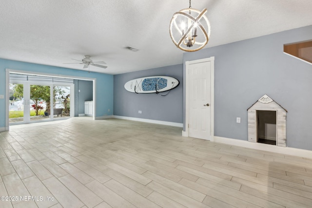 unfurnished living room with a textured ceiling, ceiling fan with notable chandelier, visible vents, light wood-style floors, and baseboards