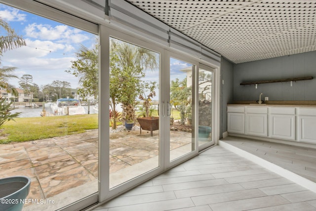 doorway featuring light wood-type flooring, a water view, and a sink