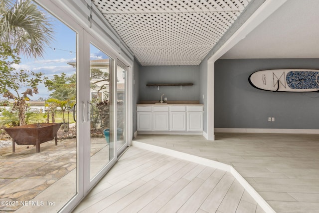 entryway with a sink, light wood-style flooring, and baseboards