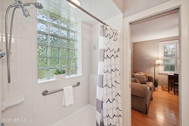 ensuite bathroom with wood finished floors, shower / bath combo with shower curtain, and connected bathroom